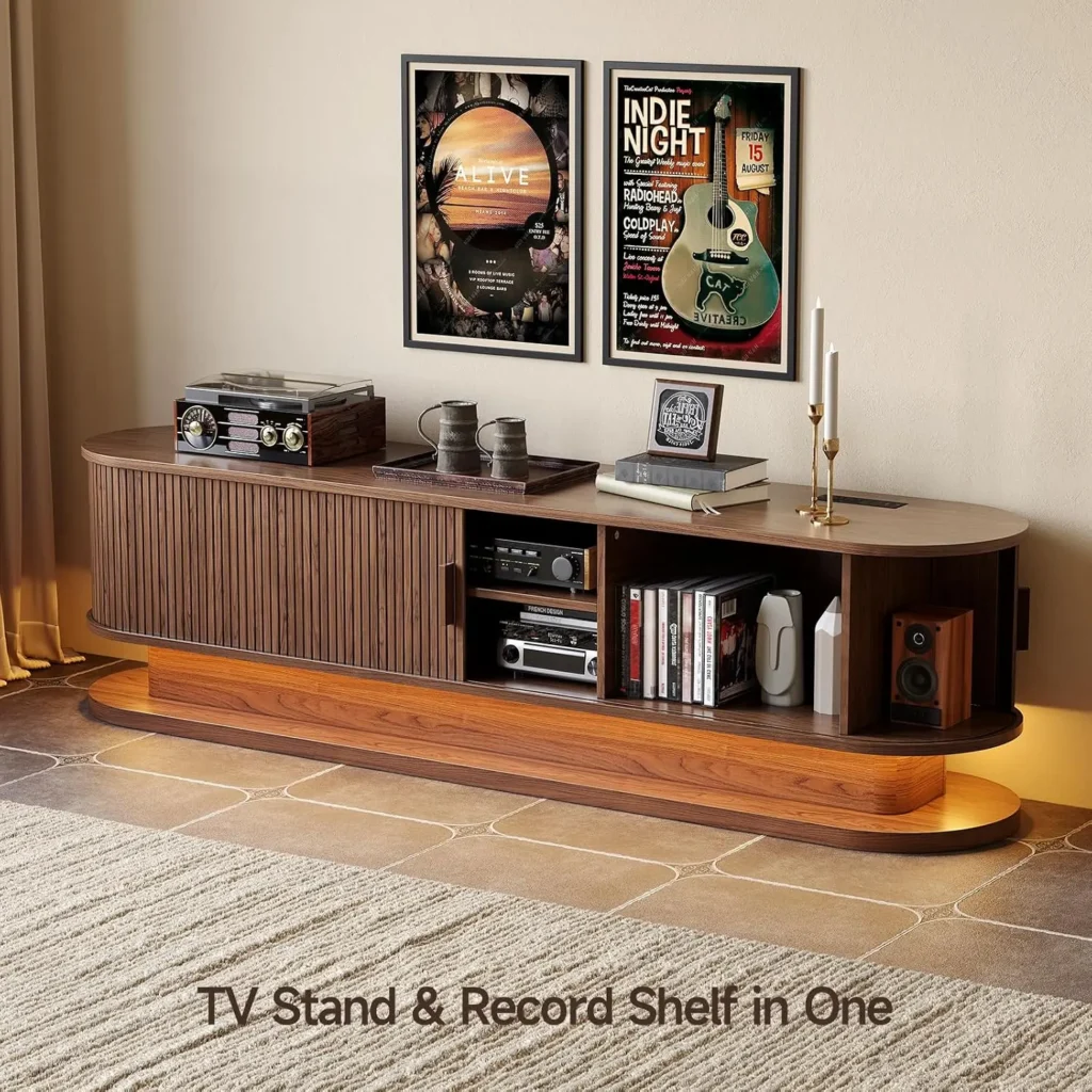 Curved walnut TV stand with a built-in record shelf, vinyl player on the left, stacked books and decorative items, and framed posters above.