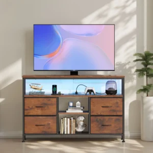 Large flat-screen TV on a wood-and-metal media cabinet, with books, gadgets, and a plant nearby in a living room.