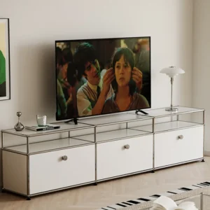 Flat-screen TV on a white chrome TV cabinet in a modern living room; the screen shows two people close up.